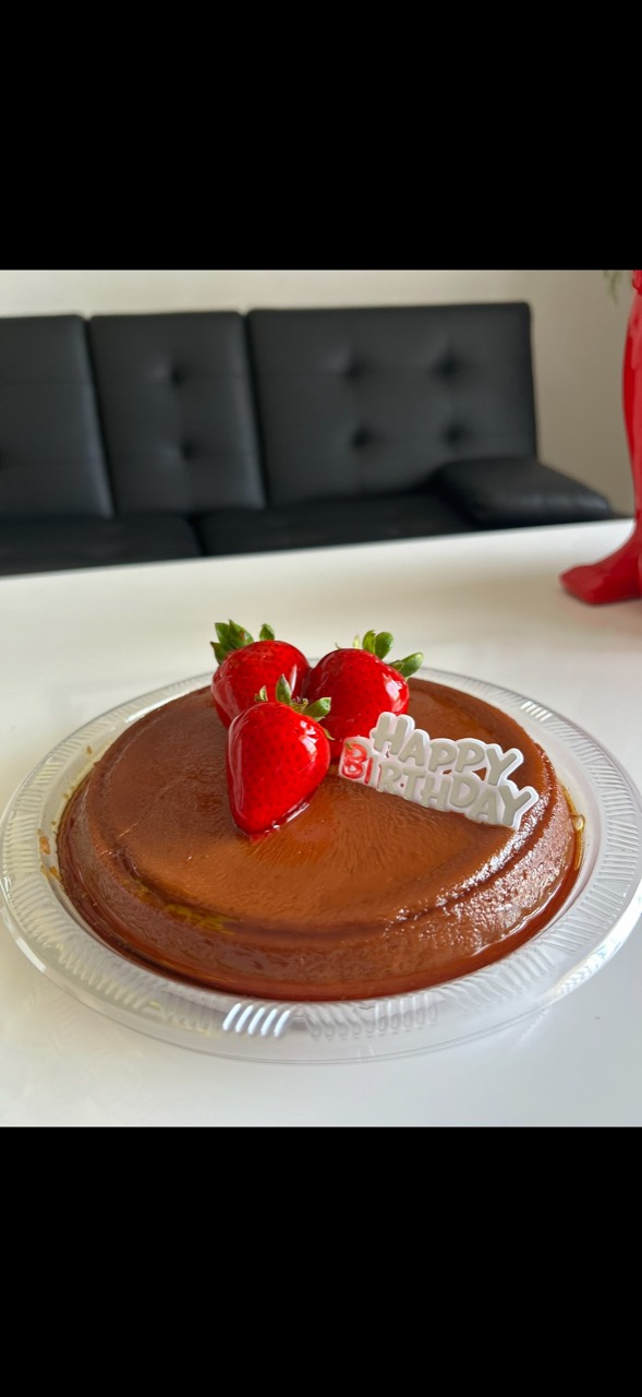 Flan con fresas y un adorno de feliz cumpleaños
